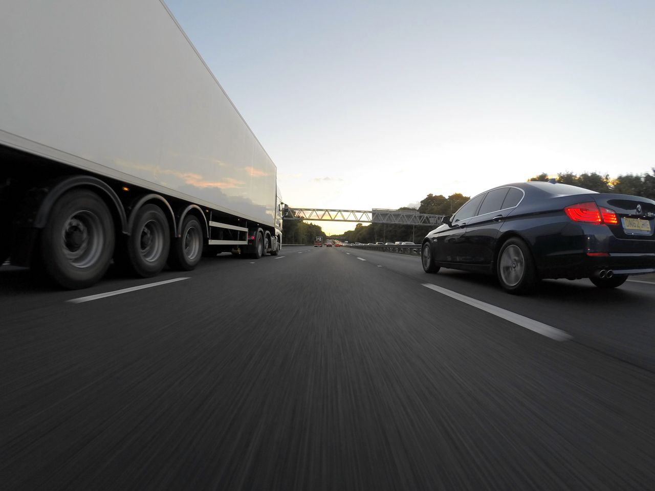 Home Cars and a truck speed along a highway under the clear sky, showcasing transportation dynamics.