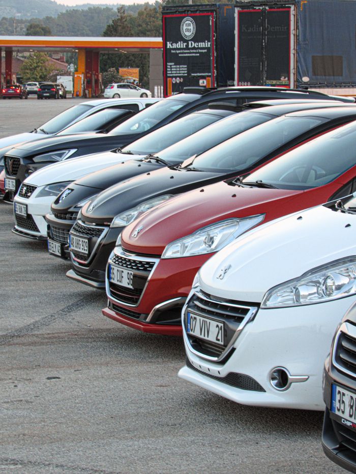 Home Lineup of modern cars neatly parked outdoors at a dealership with visible license plates.